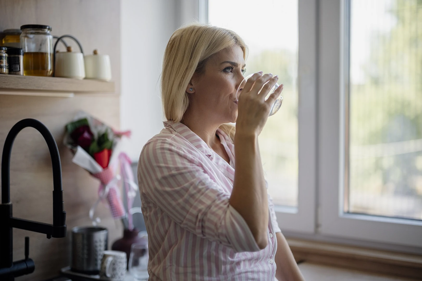 Woman drinking a glass of water in a kitchen